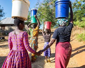 A group of women with buckets on their heads walking away.