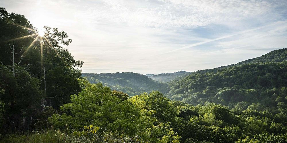 Green forested hills under a partly cloudy sky.